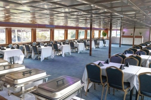 Large dining area with buffet trays, white tablecloths, and blue chairs, set for an event.