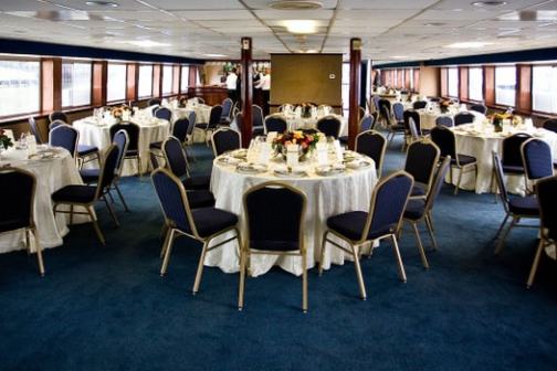 Elegant banquet hall with round tables, white tablecloths, and chairs arranged under a low ceiling.